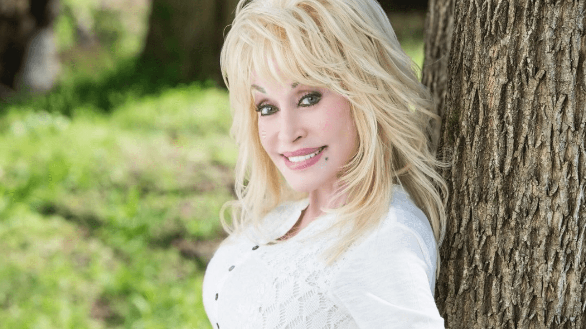 Dolly Parton Reassures Fans with a bright smile while posing outdoors, confirming her wellbeing after recent health rumors.